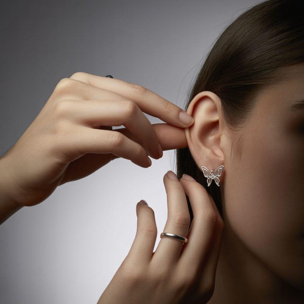 ręce trzymające kolczyk z zapięciem motylkowym